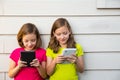 Twin sister girls playing with tablet pc happy on white wall Royalty Free Stock Photo