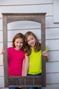 Twin sister girls posing with aged wooden border frame Royalty Free Stock Photo