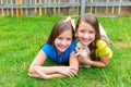 Twin sister kid girls and puppy dog lying in lawn Royalty Free Stock Photo