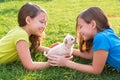 Twin sister kid girls and puppy dog lying in lawn