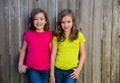 Twin sisters with different hairstyle posing on wood fence