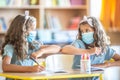 Twin sisters with face mask back at school during COVID-19 quarantine