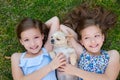 Twin sisters playing with chihuahua dog lying on lawn Royalty Free Stock Photo