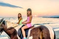 Twin sisters riding horses in the sunset by the sea on the isla Royalty Free Stock Photo