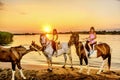 Twin sisters riding horses in the sunset by the sea on the isla Royalty Free Stock Photo