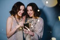 Twin sisters in shiny evening dresses celebrate with glasses of sparkling wine Royalty Free Stock Photo