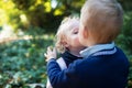 Twin toddler sibling boy and girl standing in autumn forest, kissing. Royalty Free Stock Photo