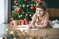 With a twinkle in her eye, a little girl writing her letter to Santa Claus Royalty Free Stock Photo