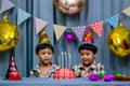 Twins adorable boy in shirt, celebrating his birthday, blowing candles on homemade baked cake, indoor. Birthday party for kids Royalty Free Stock Photo