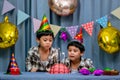 Twins adorable boy in shirt, celebrating his birthday, blowing candles on homemade baked cake, indoor. Birthday party for kids Royalty Free Stock Photo