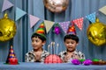 Twins adorable boy in shirt, celebrating his birthday, blowing candles on homemade baked cake, indoor. Birthday party for kids Royalty Free Stock Photo