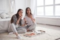 Twins have nice weekend. Sisters eating pizza when watching TV while sits on the floor of beautiful bedroom at daytime Royalty Free Stock Photo