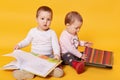 Twins sisters reading books while sitting on floor at home, charming girls playing while their mommy cooking breackfast, girls Royalty Free Stock Photo