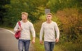 Twins walk along road. Adventure concept. Guys hitchhiking on road. Tourist traveler travel auto stop. Transporting