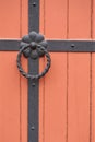 Iron doorknocker on orange wooden door