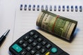 Twisted dollars, calculator on notebook and pen Royalty Free Stock Photo
