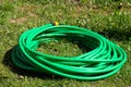 A twisted green reinforced hose for watering lies on the grass . Leningrad region.Russia