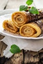 Twisted pancakes, covered with chocolate, close-up on a wooden b