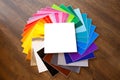 Twisted pile of colorful 12x12 sheets of adhesive paper with box isolated over the brown background. Mockup