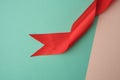 Twisted silk red ribbon on a green-beige background, top view Royalty Free Stock Photo