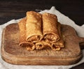 Twisted thin fried pancakes with filling lie in a stack on a wooden board