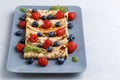 Twisted thin pancakes with raspberries and blueberries decorated with mint. Food on a gray square plate. Russian kitchen.