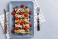 Twisted thin pancakes with raspberries and blueberries decorated with mint. Food on a gray square plate. Russian kitchen.