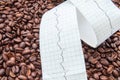 Twisted type of electrocardiogram with printed ECG line lies on fried coffee beans. Impact coffee and caffeine on heart and heart