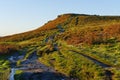 Twisting uneven muddy footpath leading up to the top of Higger Tor on a cloudless winter morning.