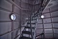 Twisting spiral staircase inside the Menomonee MI pier lighthouse with two porthole windows in the steel structure