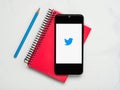 Twitter application icon on white screen of smartphone with notebook and blue pencil