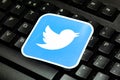 Twitter logo laying on a pc keyboard, closeup. Twitter bird square brand symbol on computer keys, detail. Tweeting, posting