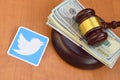 Twitter paper logo lies with judge gavel and hundred dollar bills. Entertainment lawsuit concept