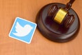 Twitter paper logo lies with wooden judge gavel. Entertainment lawsuit concept