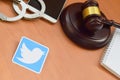 Twitter paper logo lies with wooden judge gavel, smartphone and handcuffs. Entertainment lawsuit concept