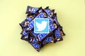 Twitter paper logo on many Snickers chocolate covered wafer bars in brown wrapping. Advertising chocolate product in Twitter