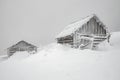 Two abandoned log cabins in winter foggy mountains Royalty Free Stock Photo