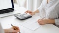 Two accountants using a calculator and laptop computer for counting taxes or revenue balance while rolls of receipts are Royalty Free Stock Photo