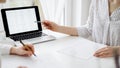 Two accountants using a laptop computer for counting taxes at white desk in office. Business Woman pointing into screen Royalty Free Stock Photo