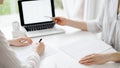 Two accountants using a laptop computer for counting taxes at white desk in office. Business Woman pointing into screen Royalty Free Stock Photo