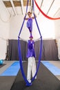 Two acrobats performing on aerial silks and stilts in a gym Royalty Free Stock Photo