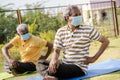 Two active senior people with medical face mask exercising on yoga mat during early morning - concept of new normal, elderly Royalty Free Stock Photo