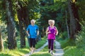 Two active seniors with a healthy lifestyle smiling while joggin