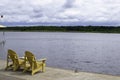 Two Adirondack chairs on a deck overlooking Lake Royalty Free Stock Photo