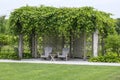 Two Adirondack Chairs Under a Grape Trellis