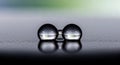 Two adjacent water droplets rest on a smooth, black surface, creating a clear Royalty Free Stock Photo