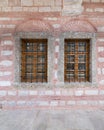 Two adjacent wooden arched windows in a red and white stone bricks wall, near Eyup Sultan Mosqoe, Istanbul, Turkey