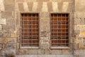 Two adjacent wooden windows with iron grid over decorated stone bricks wall, Medieval Cairo, Egypt Royalty Free Stock Photo