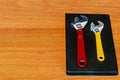 Two adjustable wrenches on brown wooden background. Classic large red adjustable wrench heads and small yellow adjustable wrench Royalty Free Stock Photo