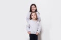 Two adorabile littel girl in sweater and jeans, posing together on white background, smiling. Posing in studio. Royalty Free Stock Photo